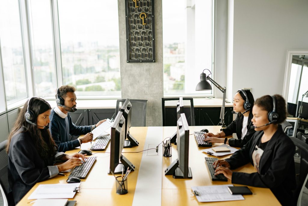Group of diverse employees working together in a modern office setting, focusing on customer service.